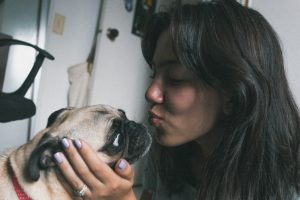 women about to kiss dog - keep a pet calm during a thunderstorm