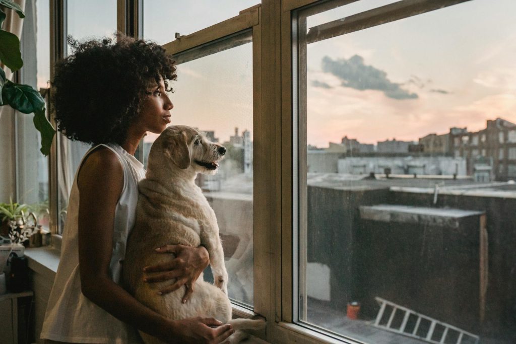 Woman cuddling dog while standing near window - pet friendly apartment upgrades