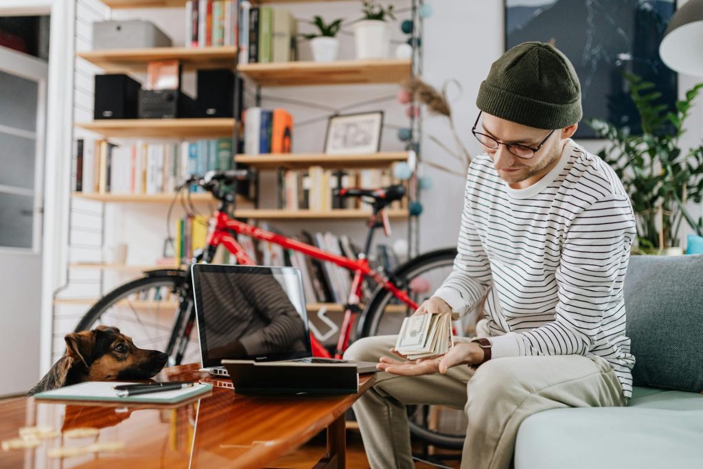 A Man in Striped Sweater Holding Cash Money - pet budgeting tips