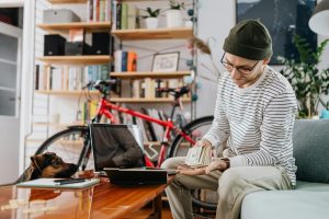 A Man in Striped Sweater Holding Cash Money - pet budgeting tips